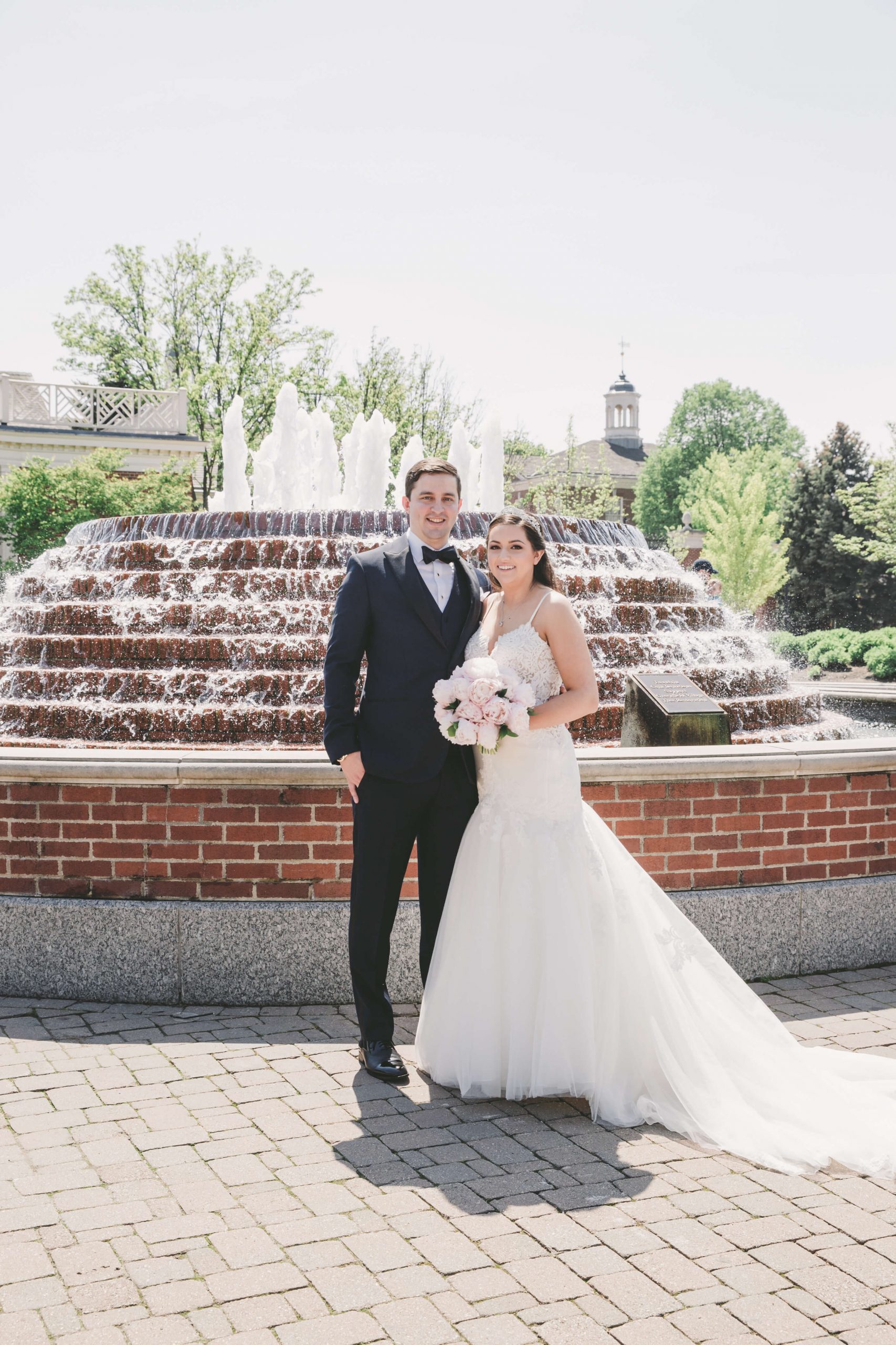 bride and groom standing in front of fountain 