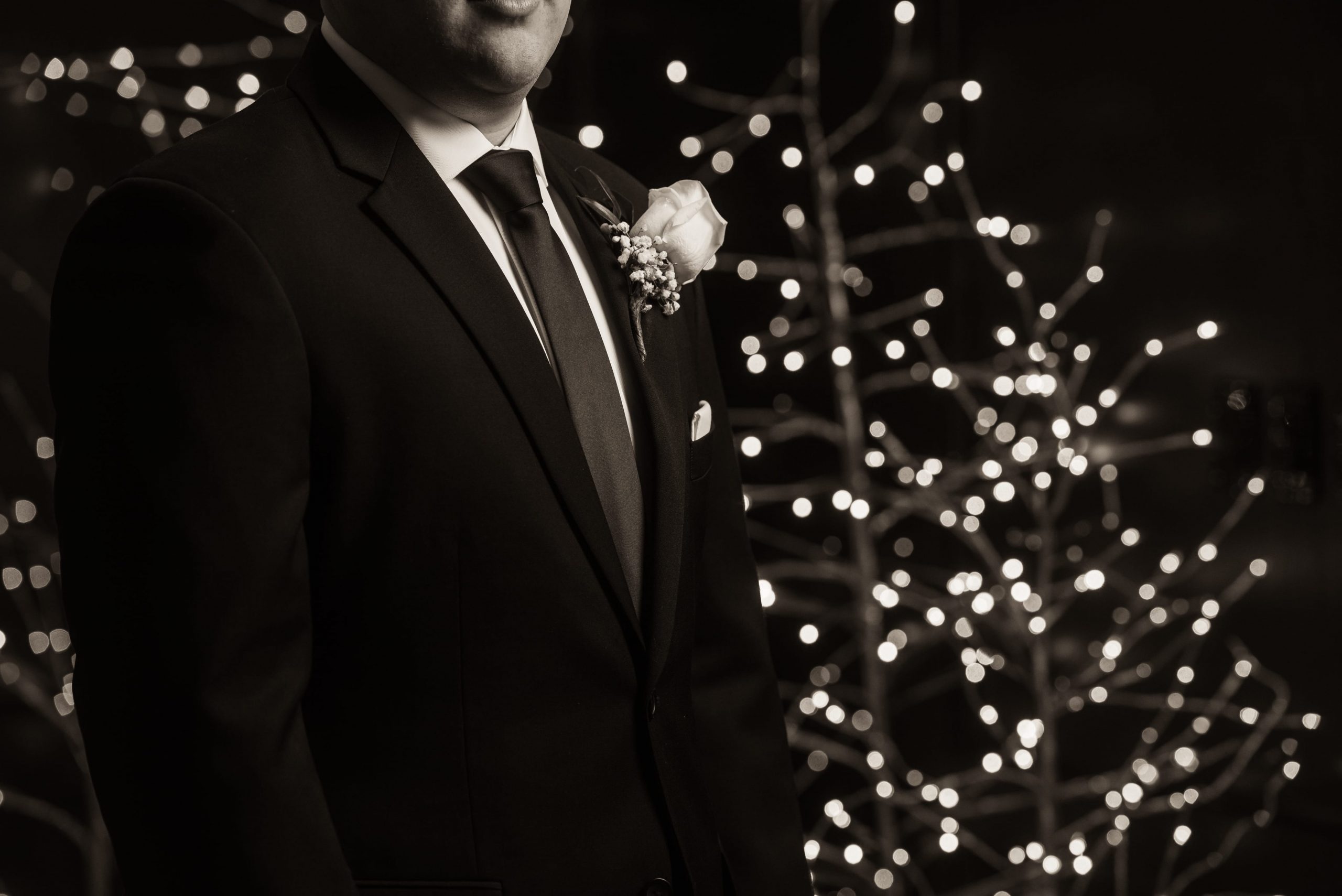 groom in front of Christmas trees