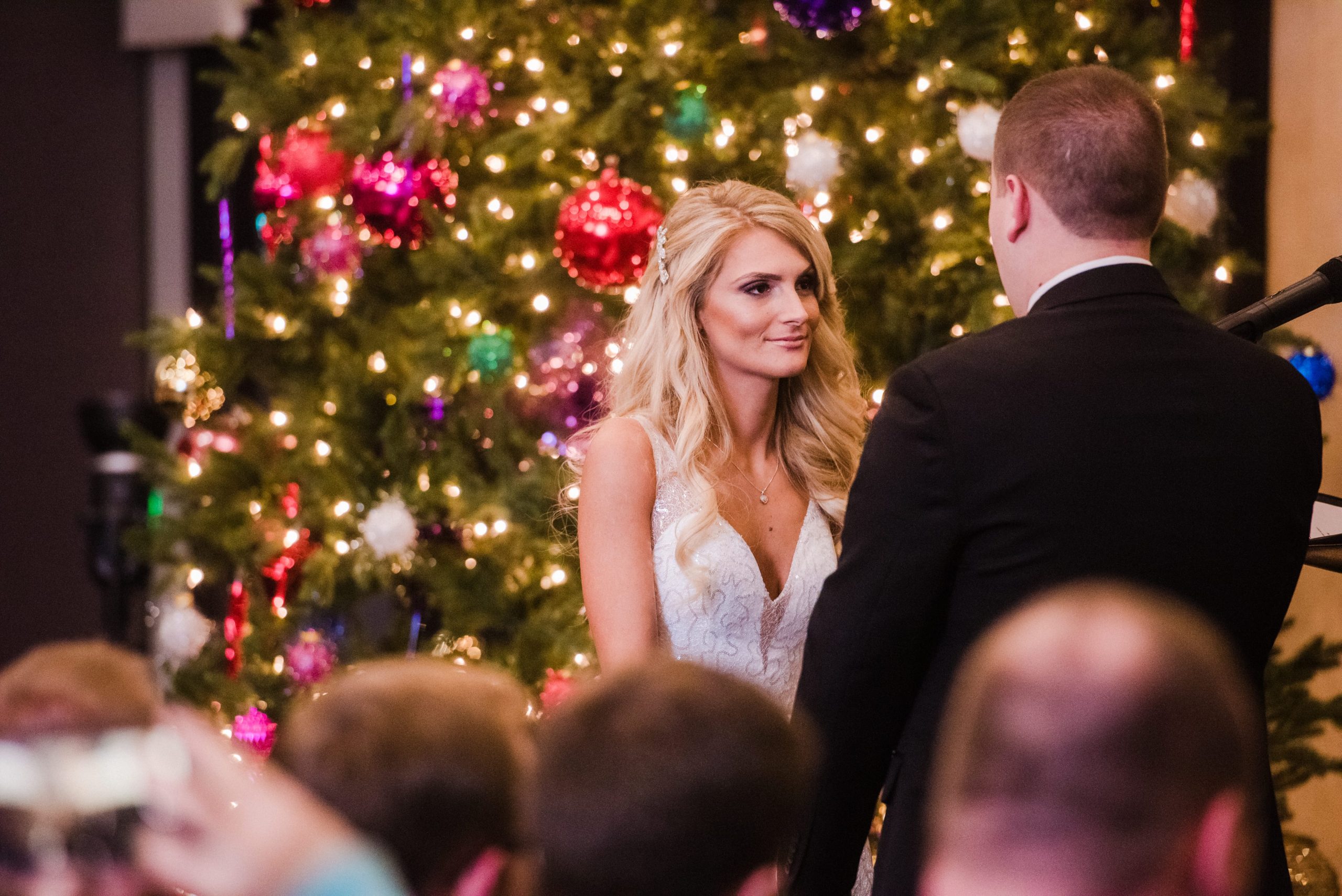 bride and groom in front of Christmas tree