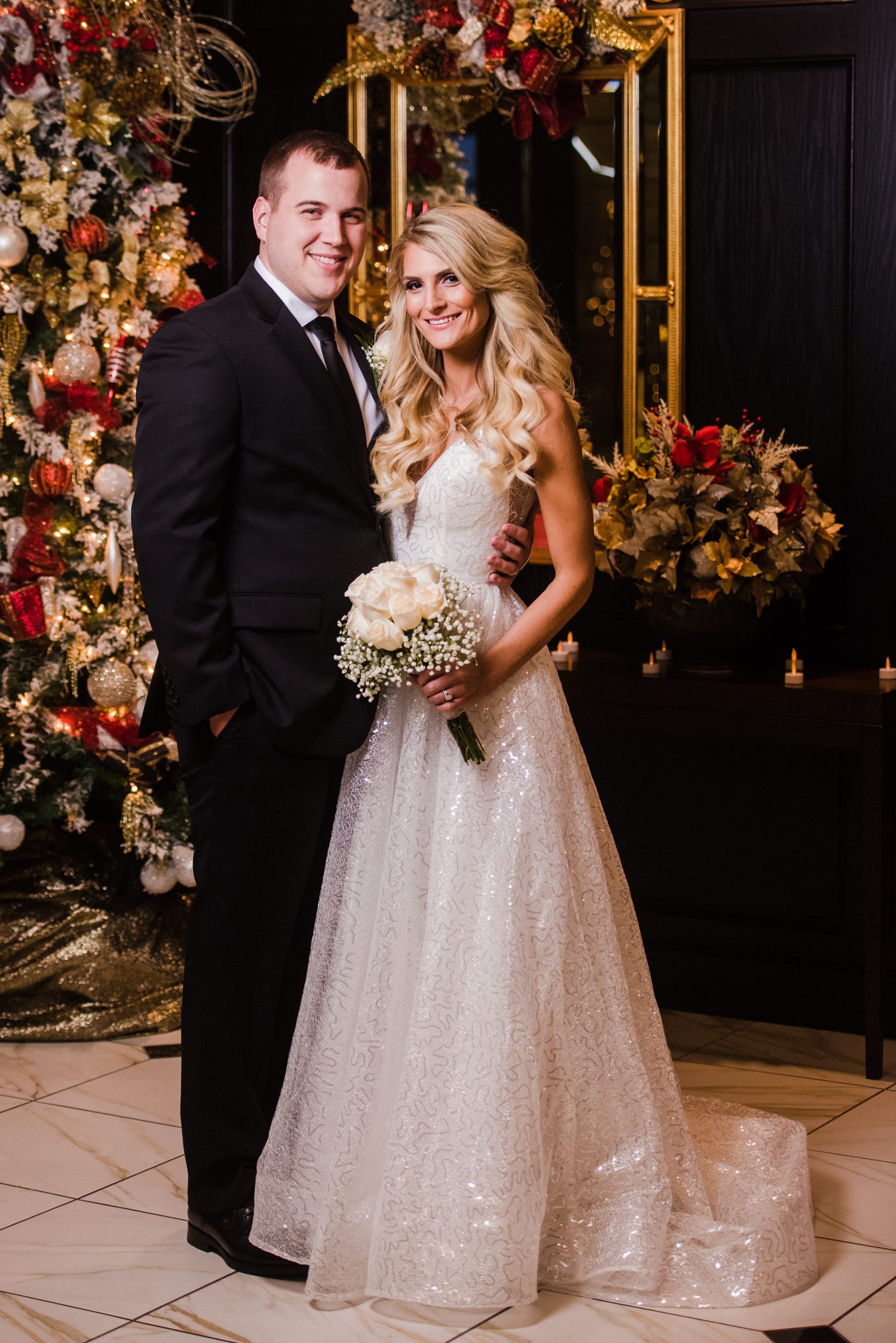 bride and groom in front of Christmas tree