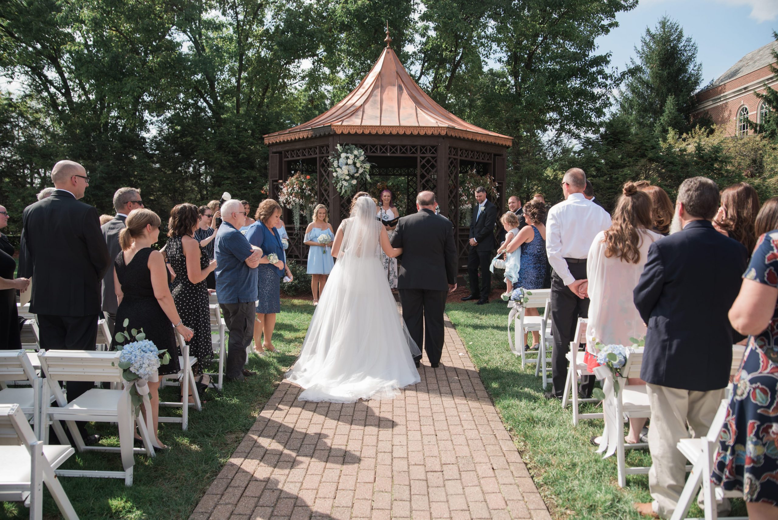 bride walking down aisle with father at outdoor ceremony