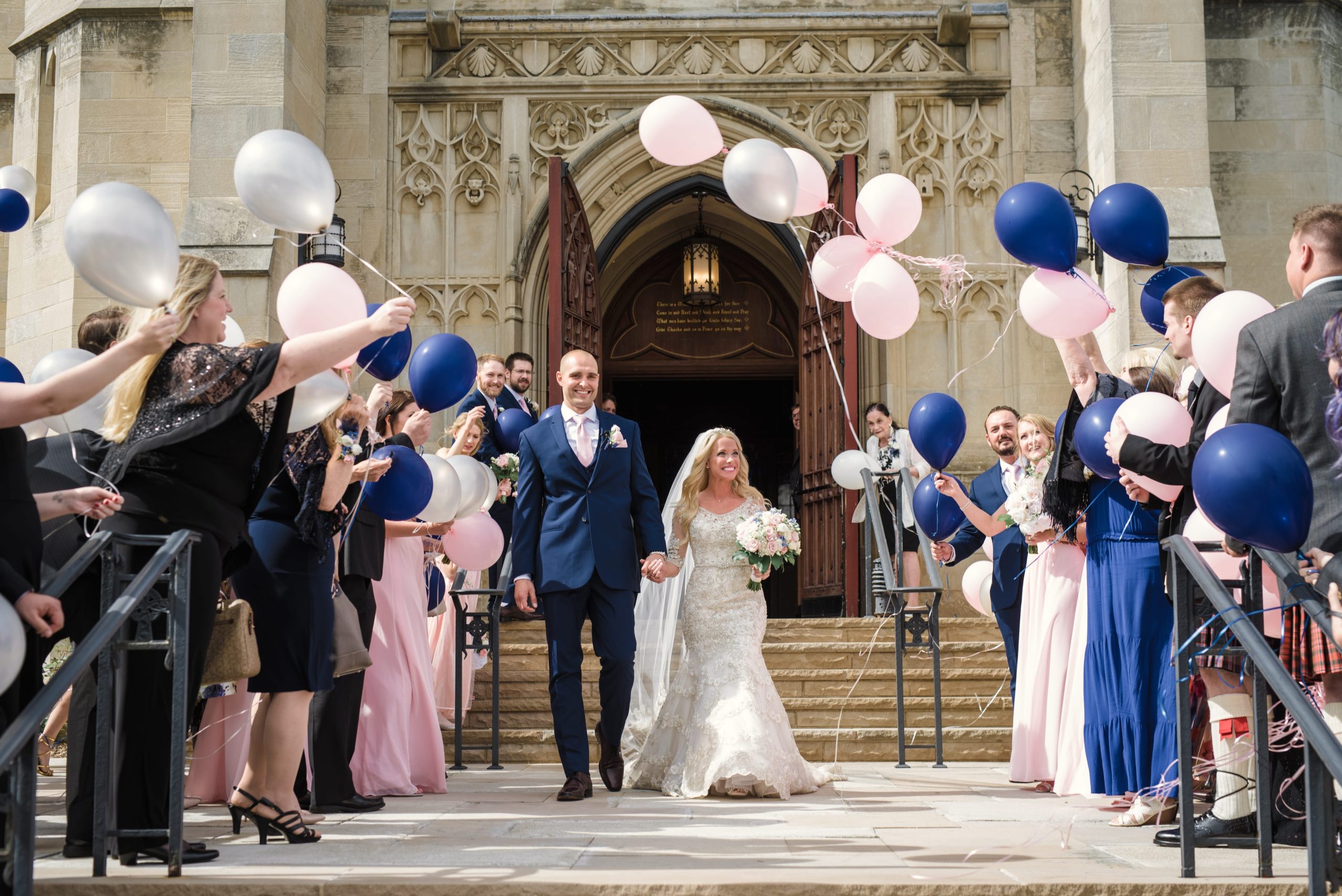 bride and groom leaving church with guests holding balloons