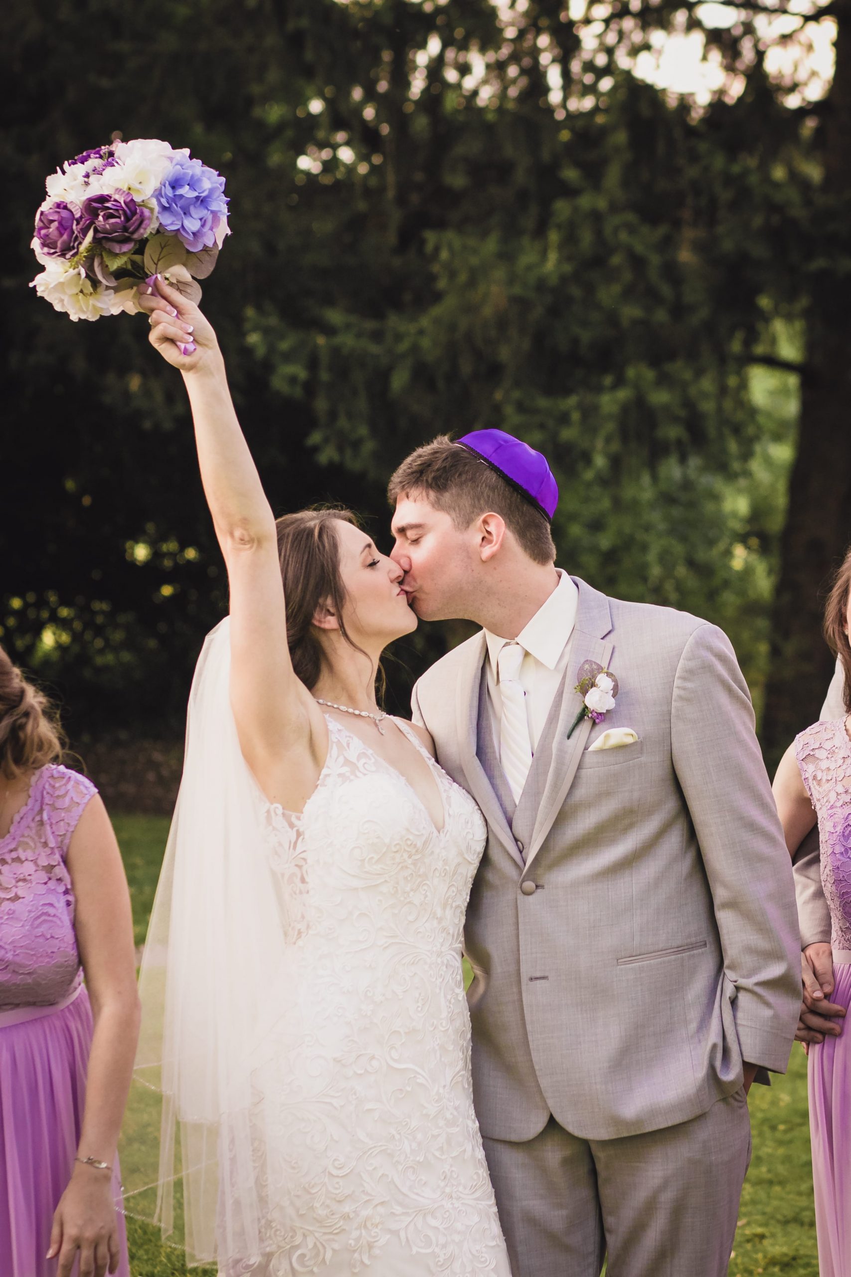 bride kissing groom while holding bouquet in the air