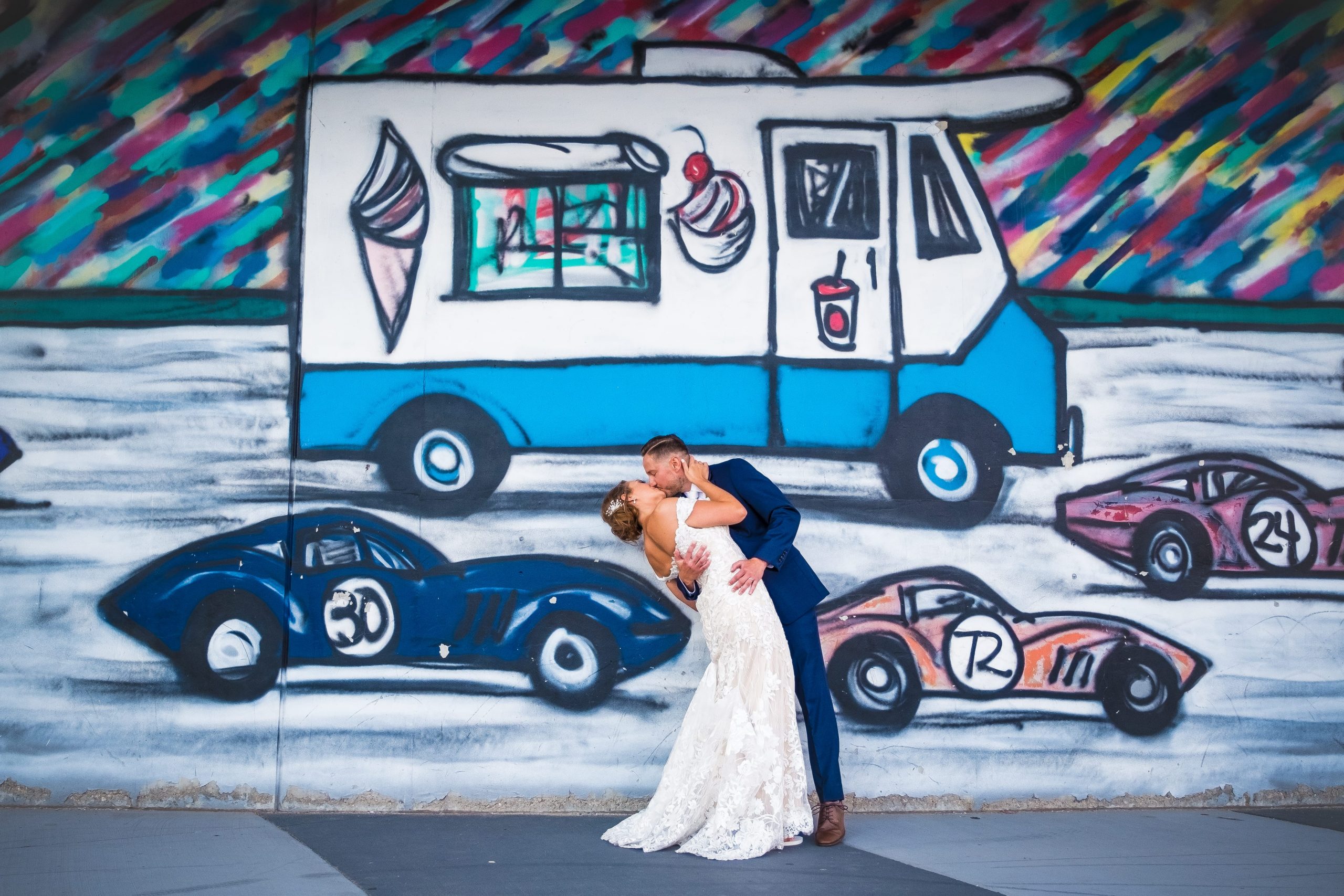 bride and groom kissing in front of detroit mural