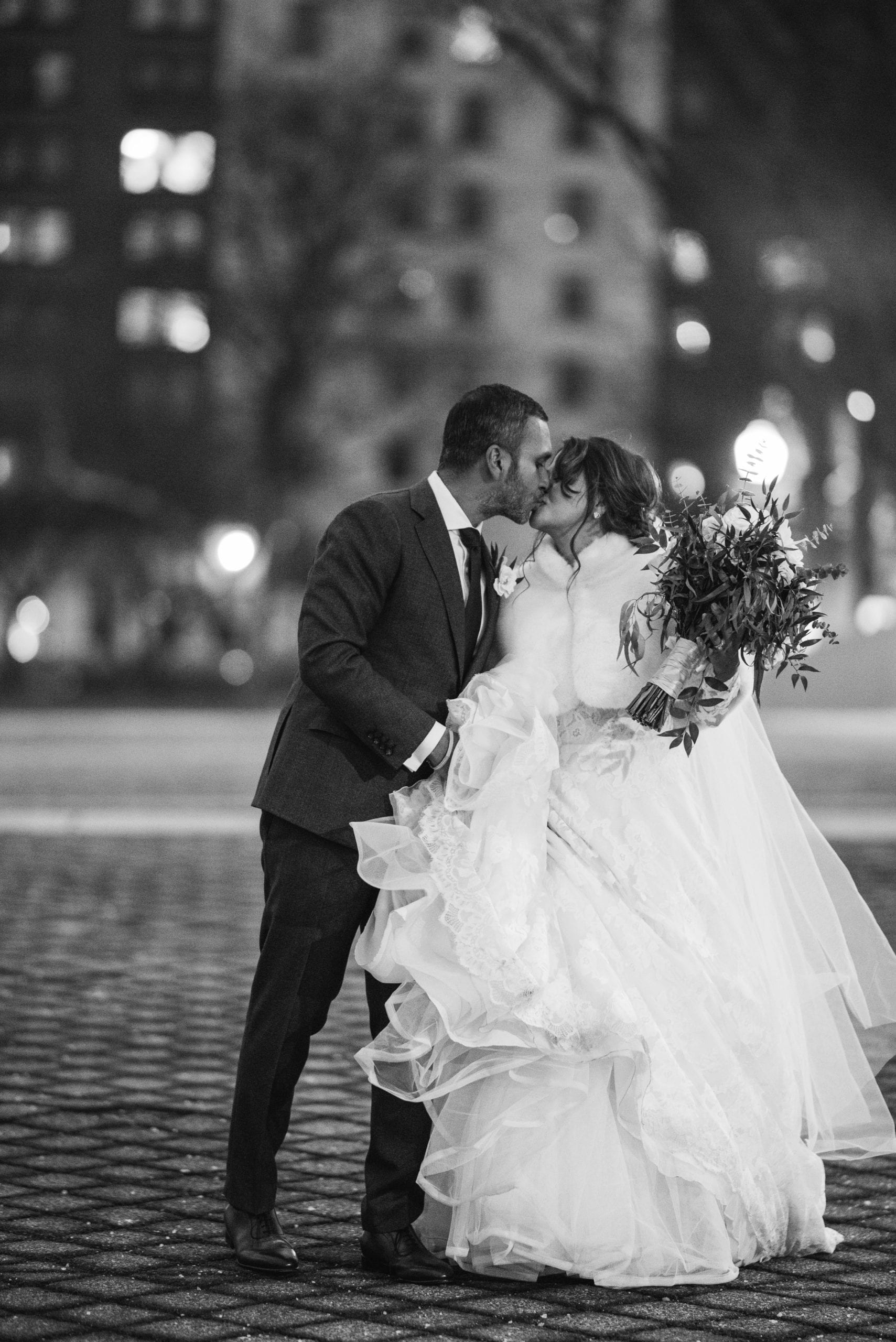 black and white photo of couple kissing downtown