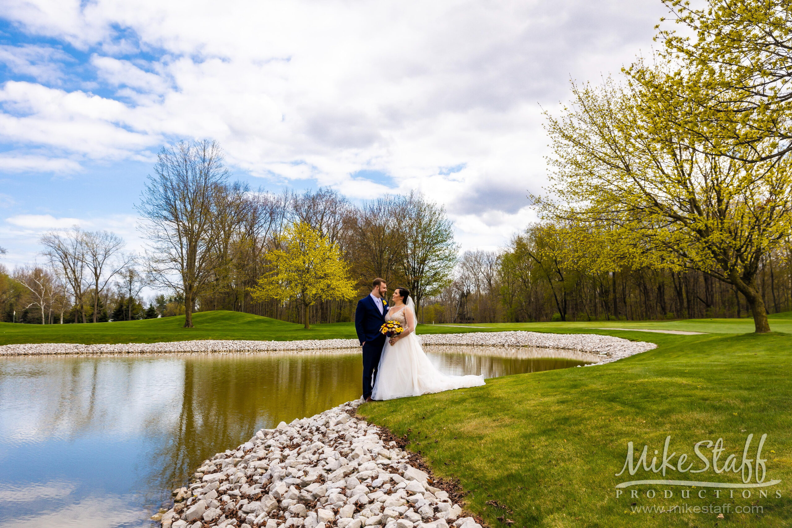 bride and groom in front of pond at sycamore hills