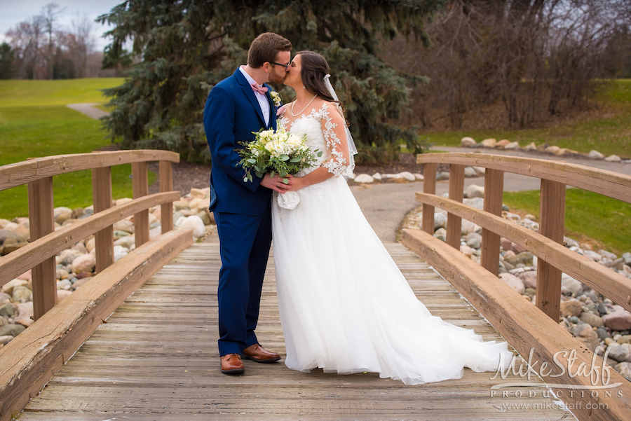 bride and groom kissing on bridge