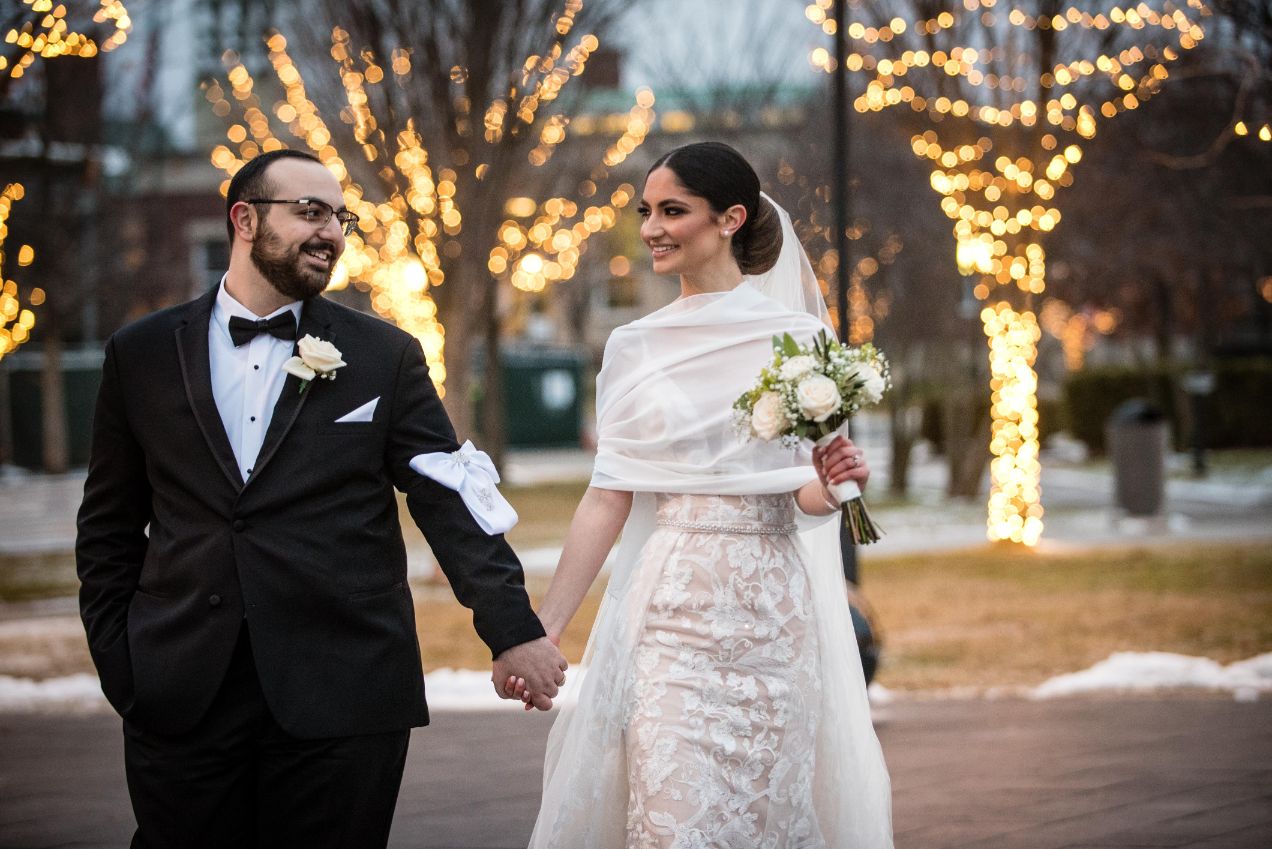 bride and groom walking outside by christmas lights