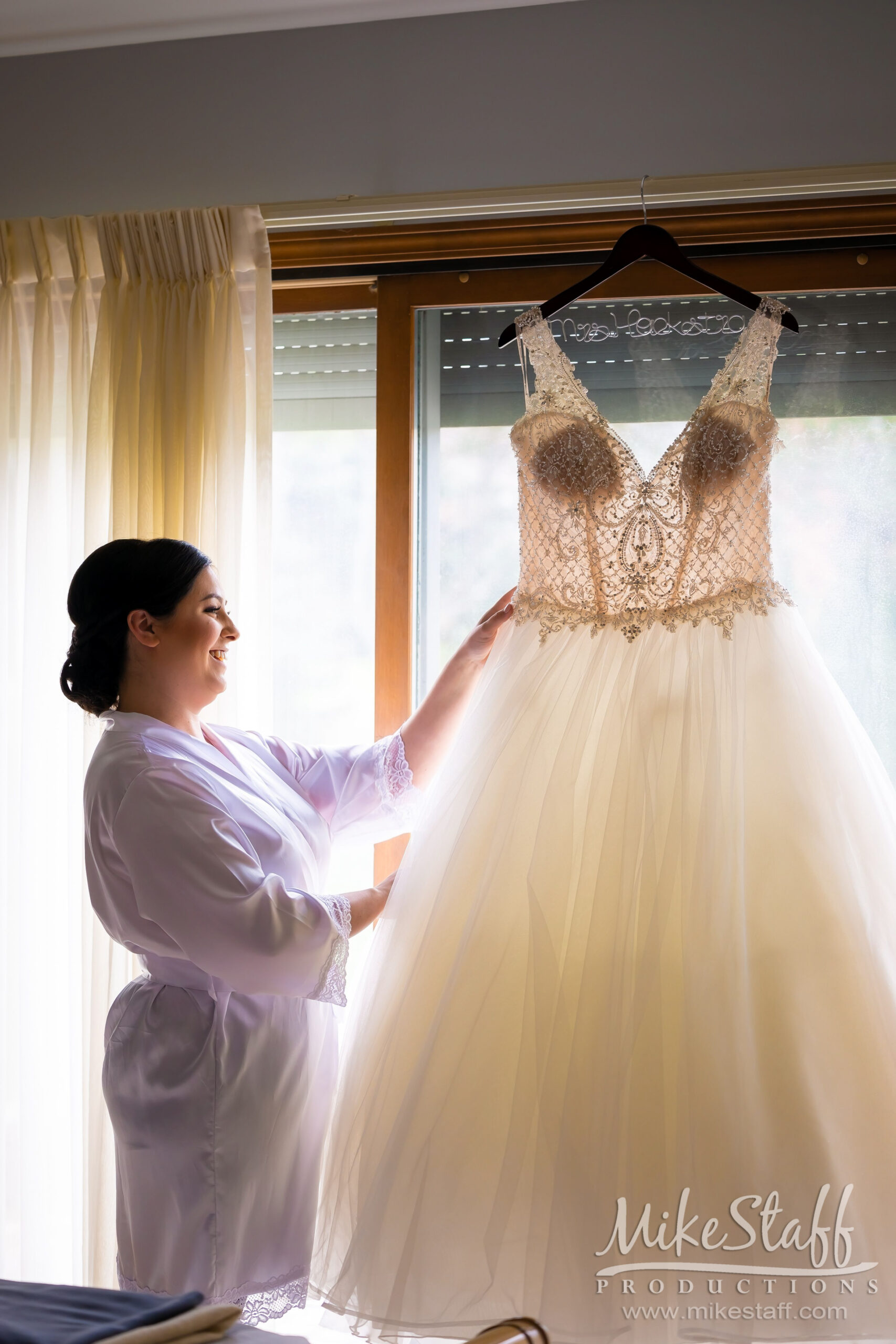 bride looking at hanging wedding dress