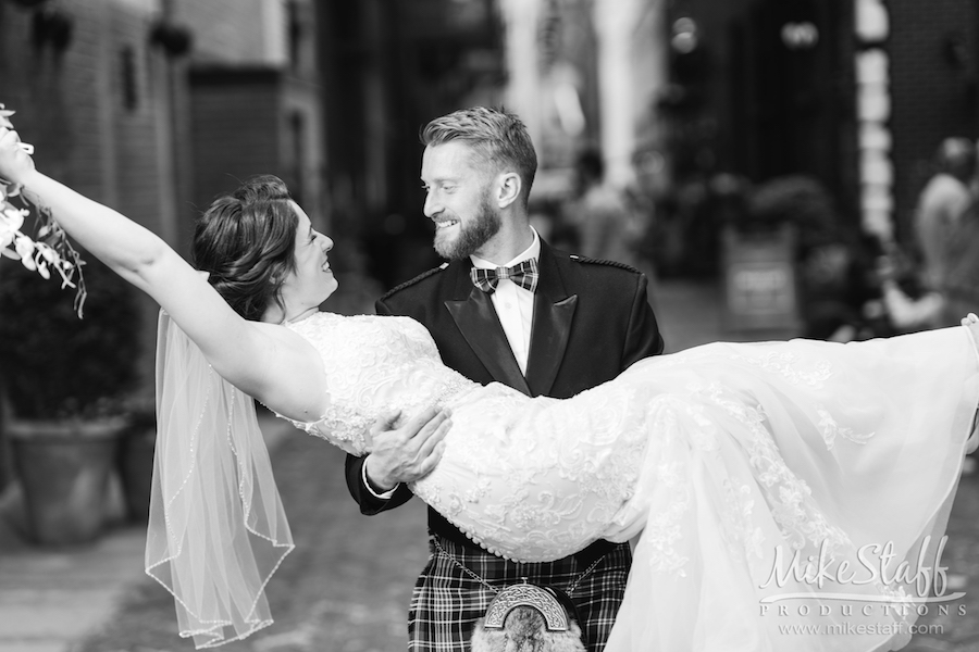 groom picking up bride throwing up bouquet